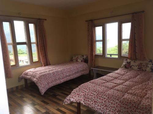 a bedroom with two beds and two windows at KB'S ECO MOUNTAIN VILLAGE HOME in Kāskī