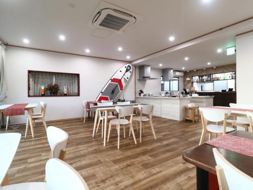 a restaurant with white tables and chairs and a kitchen at Hotel & Glamping ACT FUTTSU in Futtsu