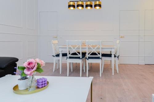 a white dining room with a table and chairs at Nida family apartments in Nida