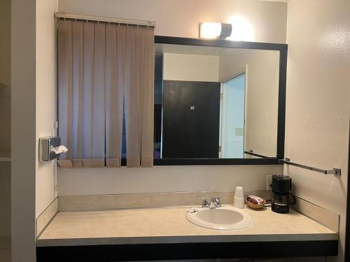 a bathroom with a sink and a large mirror at Central Motel in Fort Morgan