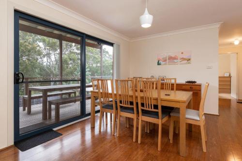 a dining room with a table and chairs and a balcony at Barrels at Boomerang in Boomerang Beach