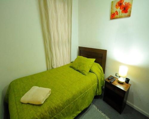 a small bedroom with a green bed and a night stand at Alojamientos San Sebastián Talca in Talca