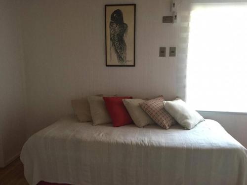 a bed with pillows on it in a room at Linda y cómoda casa interior entera/independiente in San Pedro de la Paz
