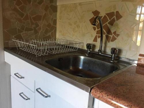 a kitchen sink with a black counter top at Linda y cómoda casa interior entera/independiente in San Pedro de la Paz