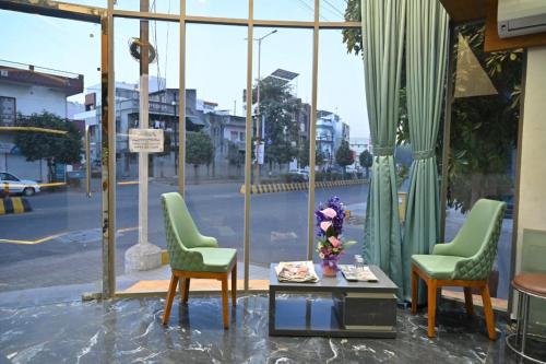 2 sillas y una mesa frente a una ventana en Hotel The Faam, en Rajkot