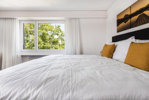 a white bedroom with a large bed and a window at SOHO 5B !Gratis Parken, Free Parking! in Kreuzlingen