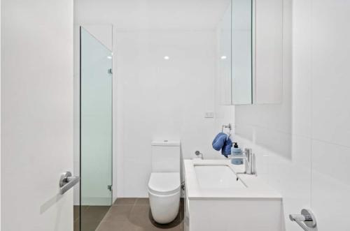 Baño blanco con aseo y lavamanos en Central, modern 1 bedroom with air-con & balcony en Sídney
