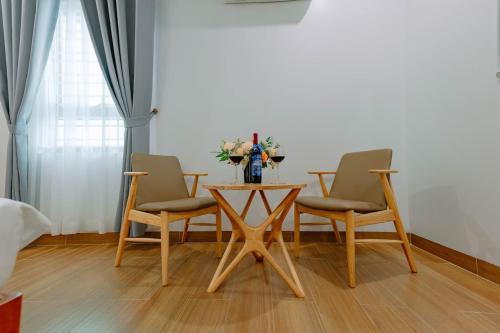 una mesa con tres sillas y un jarrón de flores. en Tuan Nam Hotel, en Hai Phong