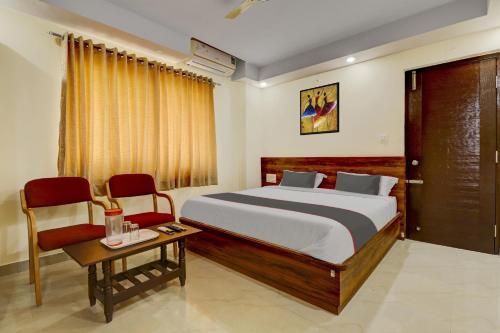 a bedroom with a bed and two chairs and a table at Collection O Hotel Hemadri Residency in Bangalore