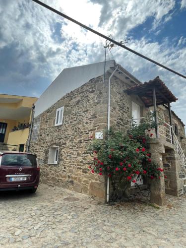 un bâtiment en pierre avec une voiture garée devant. dans l'établissement Casa do fundo do povo, 