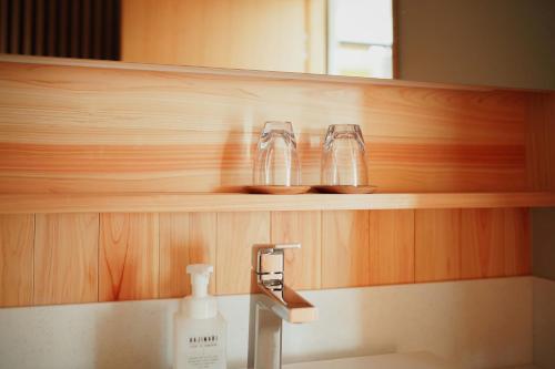 a bathroom with a sink with two glasses on a shelf at Yuyado Unzen Shinyu in Unzen