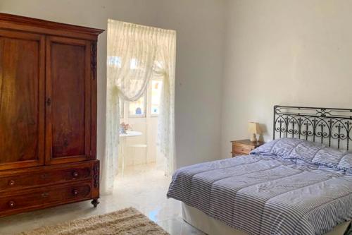 a bedroom with a bed and a dresser and a window at Bougainvillea Breeze & Marina View - Happy Rentals in Cospicua