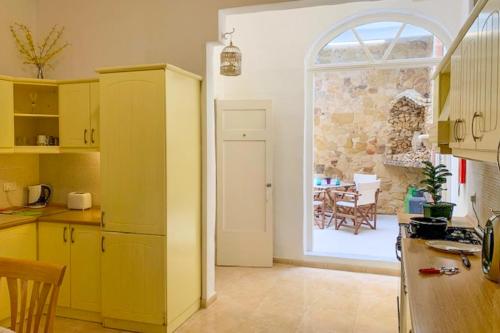 a kitchen with yellow cabinets and a door to a dining room at Bougainvillea Breeze & Marina View - Happy Rentals in Cospicua