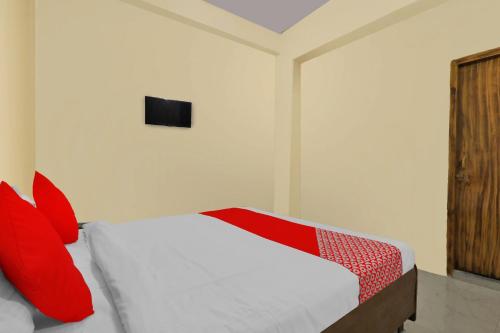 een slaapkamer met een bed met rode kussens en een televisie bij Flagship Hotel Loknath Inn in Chinhat