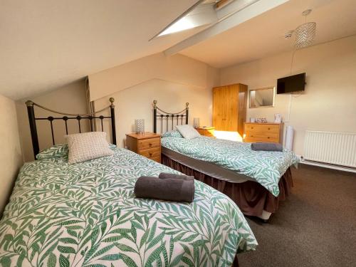 a bedroom with two beds and a tv in it at Bon-Ami in Lowestoft