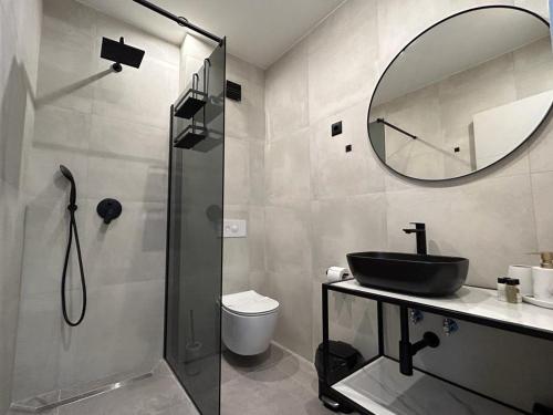 een badkamer met een wastafel en een douche met een spiegel bij Apartments Johnny in Podstrana