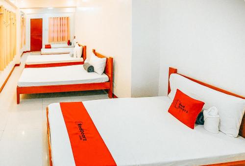 three beds in a room with red and white at RedDoorz at S & L Apartelle Daraga Albay in Legazpi