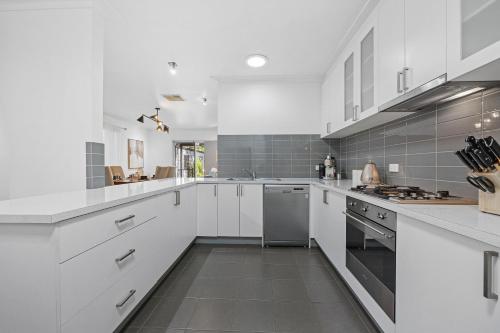 a white kitchen with white cabinets and appliances at Ballarat Cozy Cottage for Families, Sleeps 8, Pet Friendly, Big backyard, Parking for 4 cars, Close to Shopping mall in Ballarat
