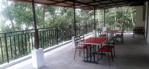 a patio with tables and chairs on a balcony at ROYAL GRAND Homestay & Resort in Vālpārai