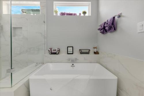 a white bathroom with a tub and a window at Azaliah Luxe Connection in Houston