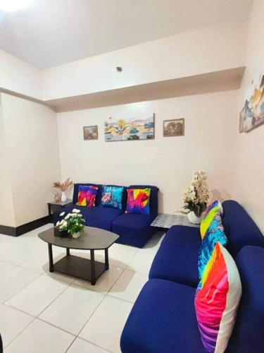 una sala de estar con sofás azules y una mesa. en Spacious 3BR Condo Unit with Wi-Fi and pool access in San Juan near Greenhills, en Manila