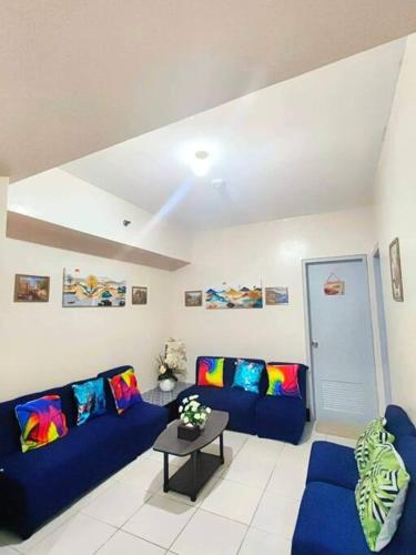 una sala de estar con 2 sofás azules y una mesa. en Spacious 3BR Condo Unit with Wi-Fi and pool access in San Juan near Greenhills, en Manila
