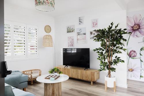 a living room with a flat screen tv on a white wall at Little Beach Boutique Apartment A- Pet Friendly in Nelson Bay