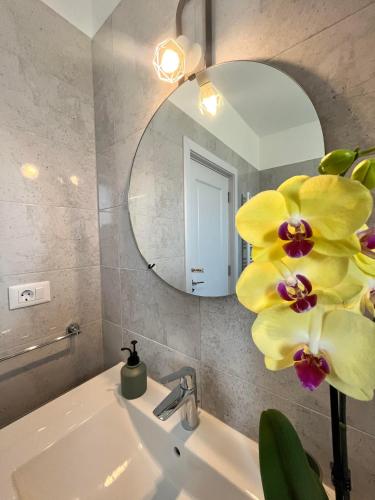 a bathroom with a sink with a mirror and a yellow flower at Dio's Apartment 29F-1 in Sfîntu Ilie