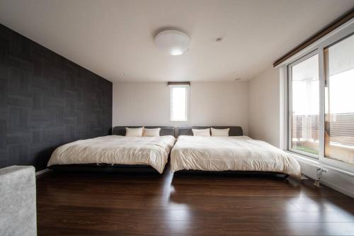a bedroom with two beds and a large window at The BEEHIVE KAMIFURANO in Kami-furano