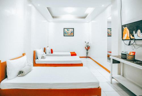 Duas camas num quarto branco com toques laranja em RedDoorz S&L Apartelle Daraga Albay em Legazpi