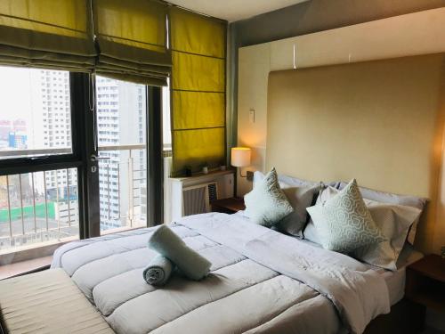 a bedroom with a large bed with a large window at One Bedroom with Netflix at Legaspi Village Makati in Manila