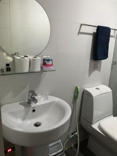 een badkamer met een wastafel, een toilet en een spiegel bij Condo hotel MAKATI GREENBELT in Manilla