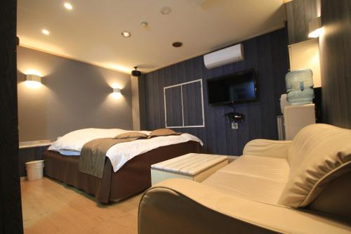 a bedroom with two beds and a couch and a tv at Hotel White Story (Adult Only) in Ibaraki