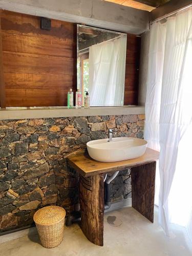 a bathroom with a sink and a stone wall at Watersmeet Glamping in Deraniyagala