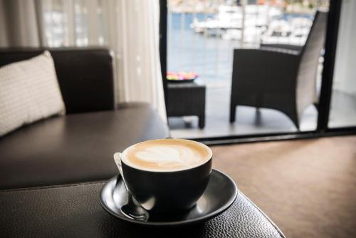 a cup of coffee sitting on a table with a spoon at Pier 21 Riverside Apartment Hotel in Fremantle