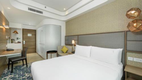 a hotel room with a white bed and a desk at Holiday Inn Gurugram Sector 90 by IHG in Gurgaon