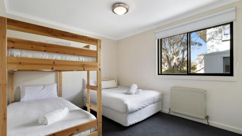 two bunk beds in a room with a window at Lawlers 30 in Mount Hotham