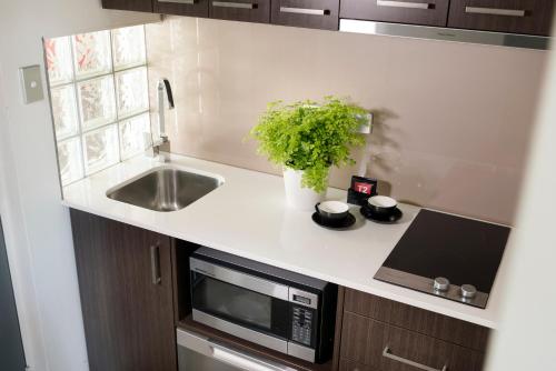 a kitchen with a sink and a microwave at Pier 21 Riverside Apartment Hotel in Fremantle