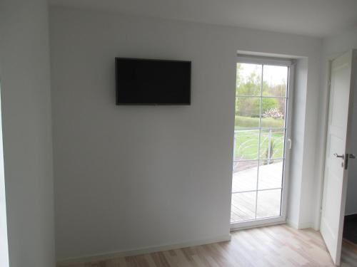 a white room with a television on a wall next to a door at White House Hotel Apartments in Brande