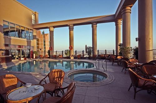 una gran piscina con sillas y una mesa en un edificio en Oryx Hotel, en Abu Dabi