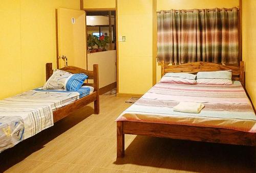 two beds in a room with yellow walls at Shandy's Transient House in Palompon