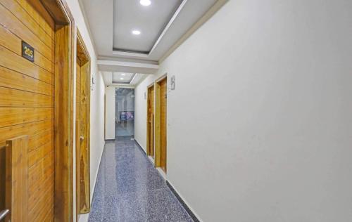 un couloir avec des murs blancs et une porte en bois dans l'établissement Meera Eternity, à Noida