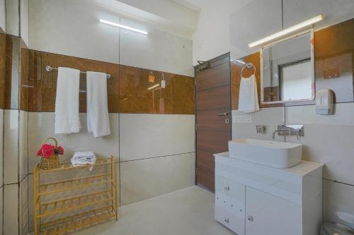 a white bathroom with a sink and a mirror at SaffronStays Summer Estate in Kasauli