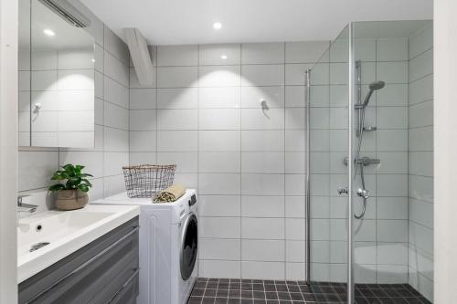 a bathroom with a washing machine and a shower at 1-Roms toppleilighet på tangen/bystranda in Kristiansand
