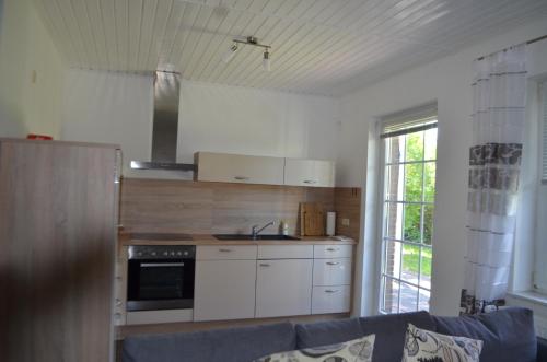 a kitchen with white cabinets and a blue couch at Yacht im Schiffehaus in Wangerland