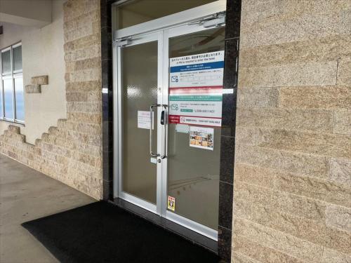 a glass door with a sign on the side of a building at HOTEL PACIFIC VIEW Rental car included & pet-friendly in Okinawa City