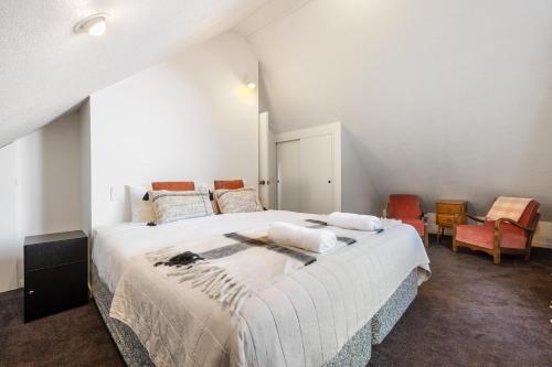 1 dormitorio blanco con 1 cama grande y sillas en Remarkable Alpine Holiday Home en Queenstown