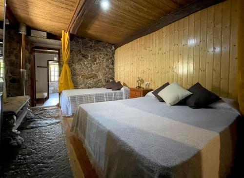 1 dormitorio con 2 camas y pared de piedra en Casa Rural Aradiña, en Covelo