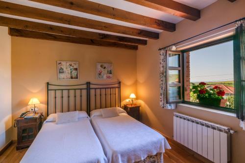 2 camas en un dormitorio con ventana en Posada Caborredondo en Santillana del Mar