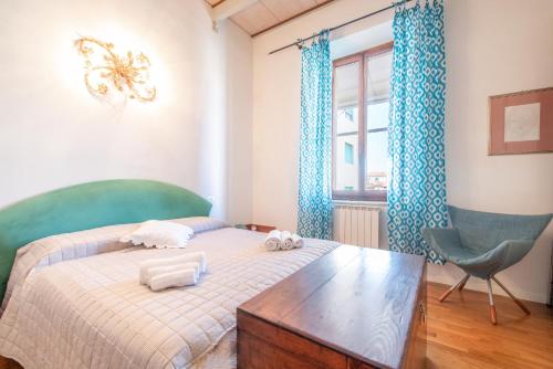 a bedroom with a bed and a chair and a window at Piombino Apartments - Casa Fucini in Piombino